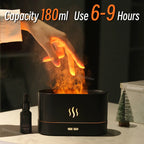 Black humidifier with flames and text indicating capacity and usage time, placed on a surface with a bottle and small tree decoration.