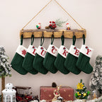 Set of green Christmas stockings with embroidered letters spelling 'LUCKY' hanging on a wooden shelf.
