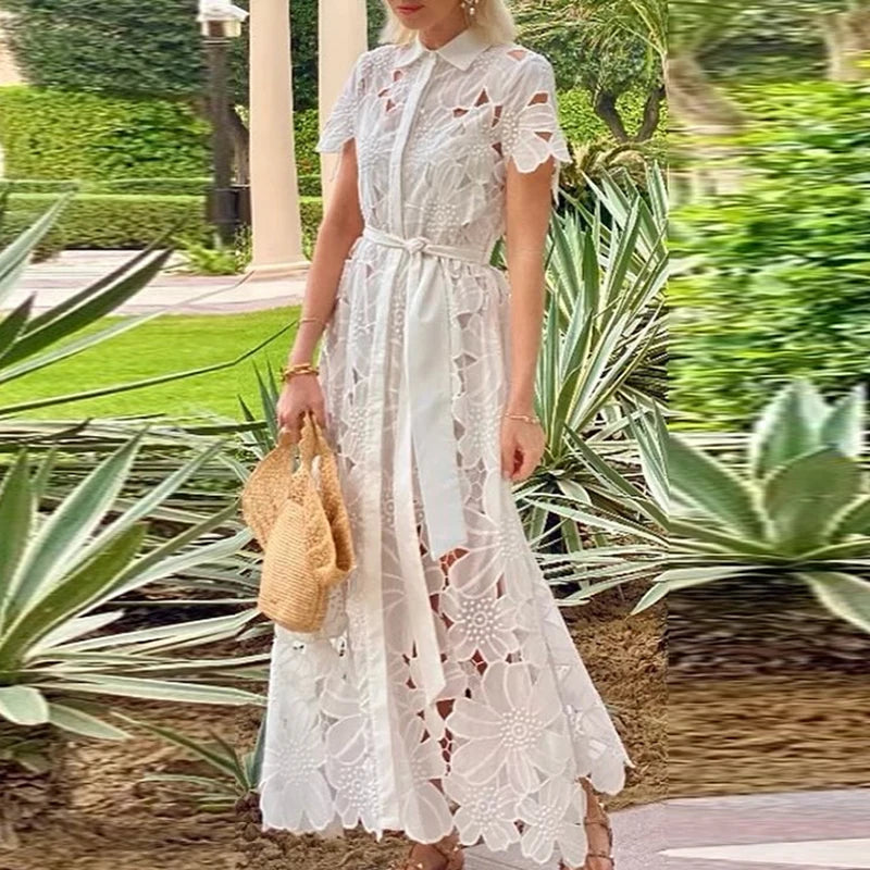 Woman in a white lace dress holding a straw bag in a garden setting
