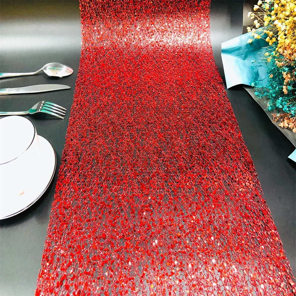 Red glittery table runner on a black surface with silverware and a decorative item.