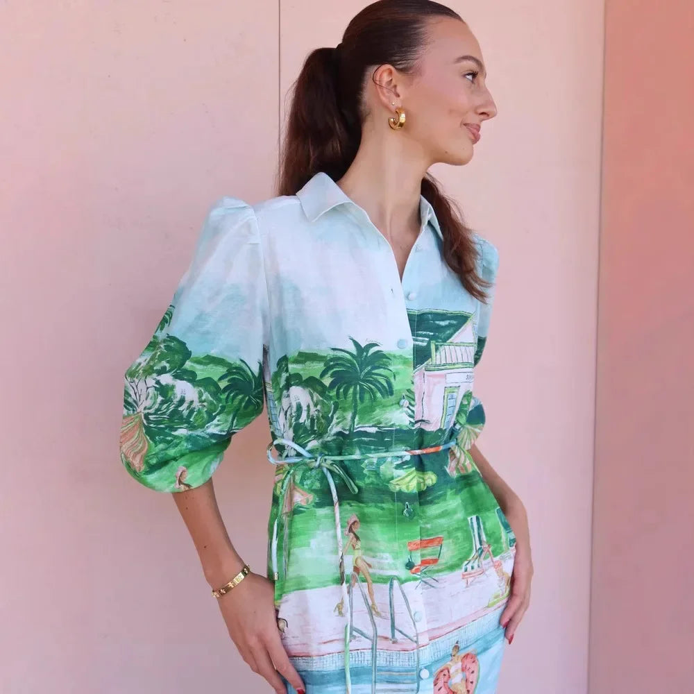 Woman wearing a colorful dress with a tropical pattern against a pink background