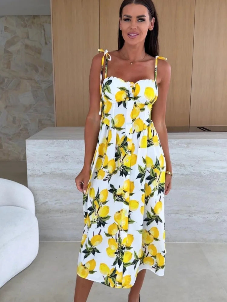 Woman wearing a white dress with yellow lemon print in an indoor setting.