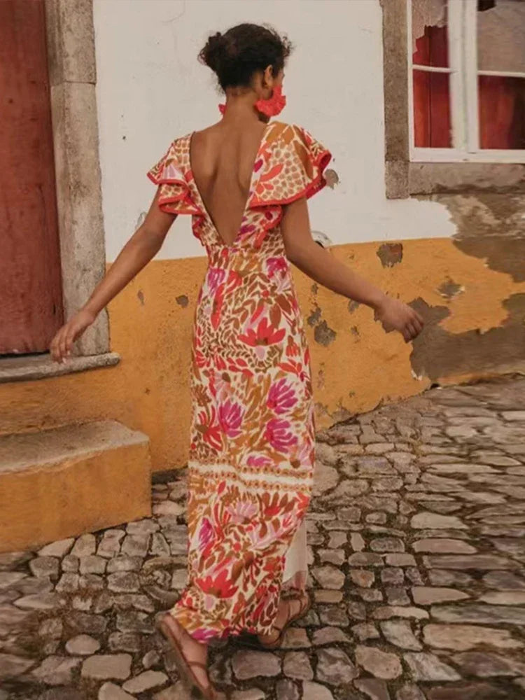 Woman in a floral dress walking on a cobblestone street.