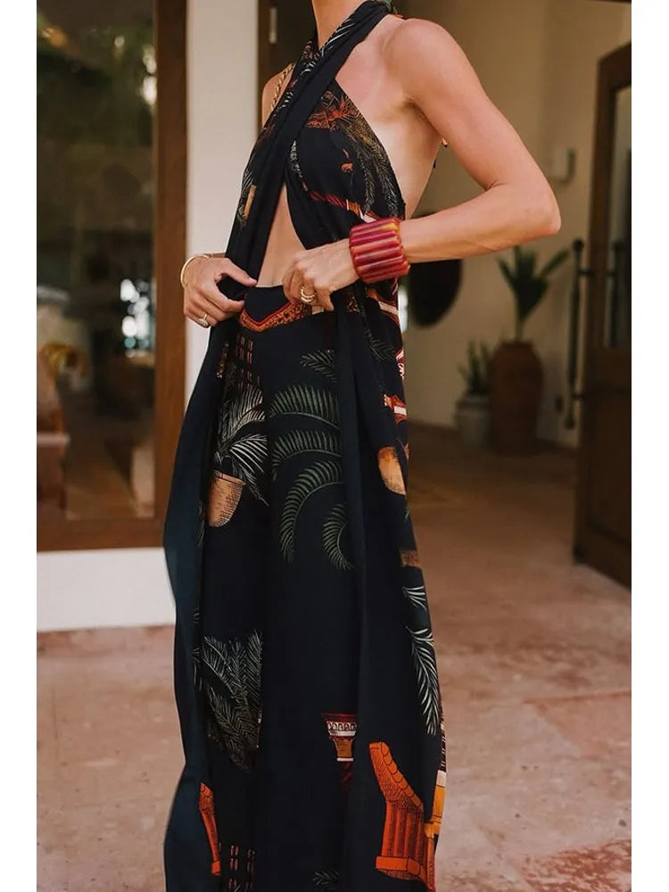 Person wearing a black dress with tropical leaf patterns in an indoor setting.