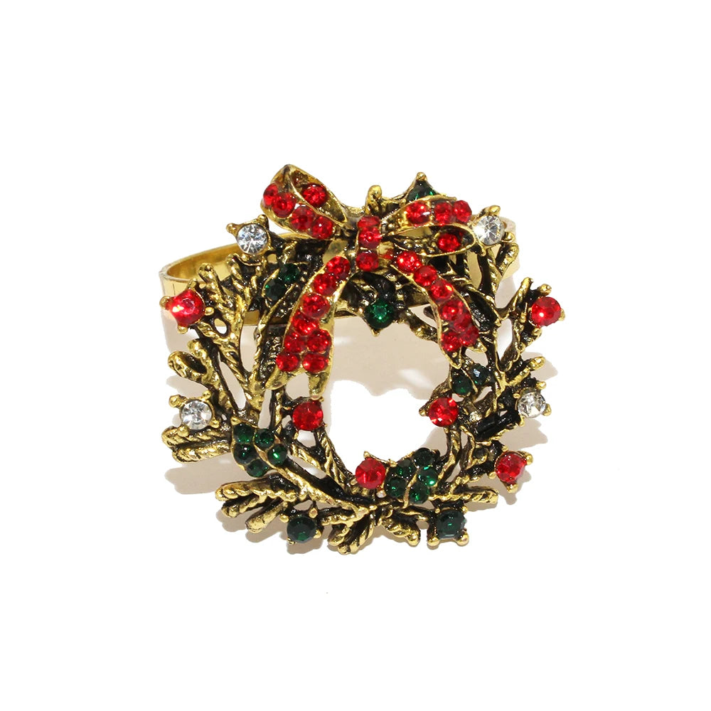Gold wreath brooch with red and green gemstones on a white background