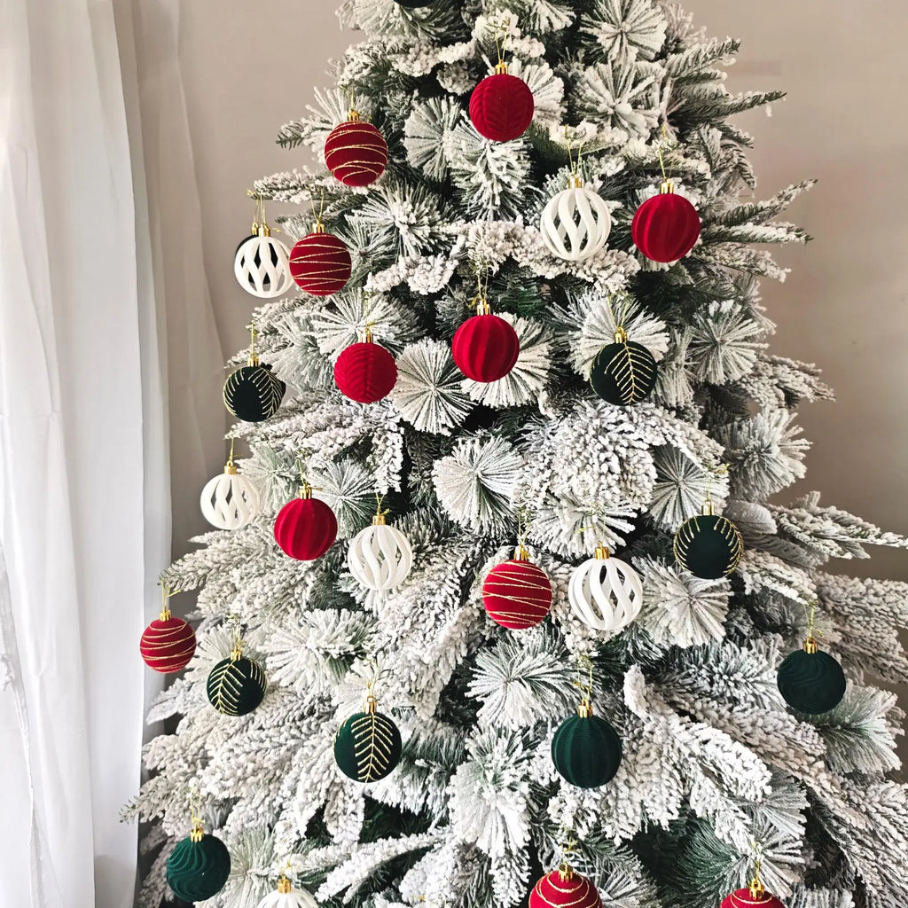 Decorated Christmas tree with red, white, and green ornaments against a neutral wall.