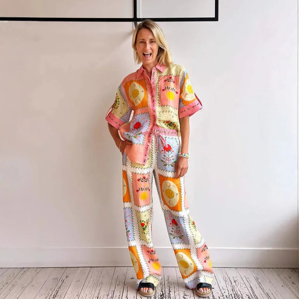 Woman wearing a colorful, patterned outfit standing against a plain wall.