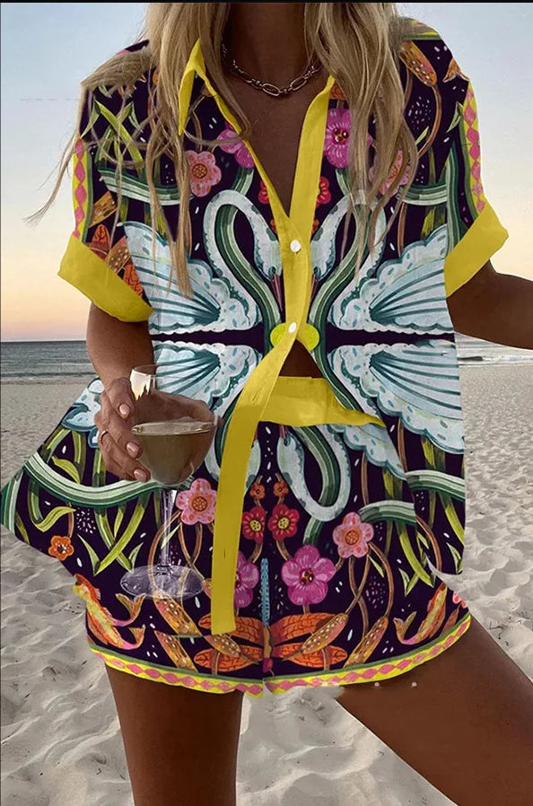 Woman in a colorful butterfly-patterned dress on a beach.