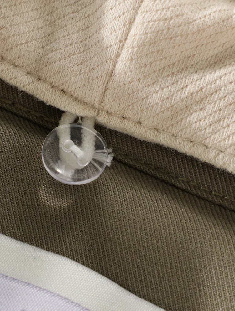 Close-up of a beige fabric with a clear plastic clip attached, on a brown background.