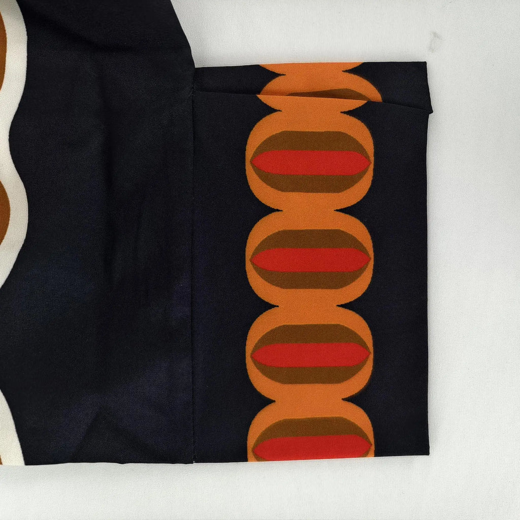 Black fabric with a pattern of orange and red circles on a white background