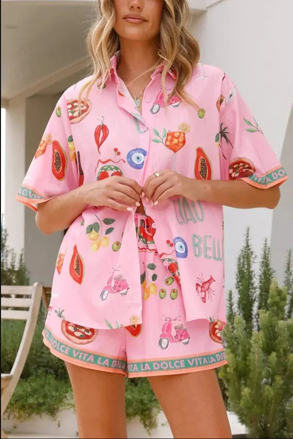 Person wearing a pink pajama set with colorful fruit and animal prints outdoors.