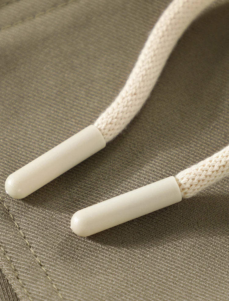 Close-up of beige shoelaces with white plastic tips on a textured fabric background