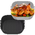 Roasted chicken with vegetables on a white plate, accompanied by a black textured pan.
