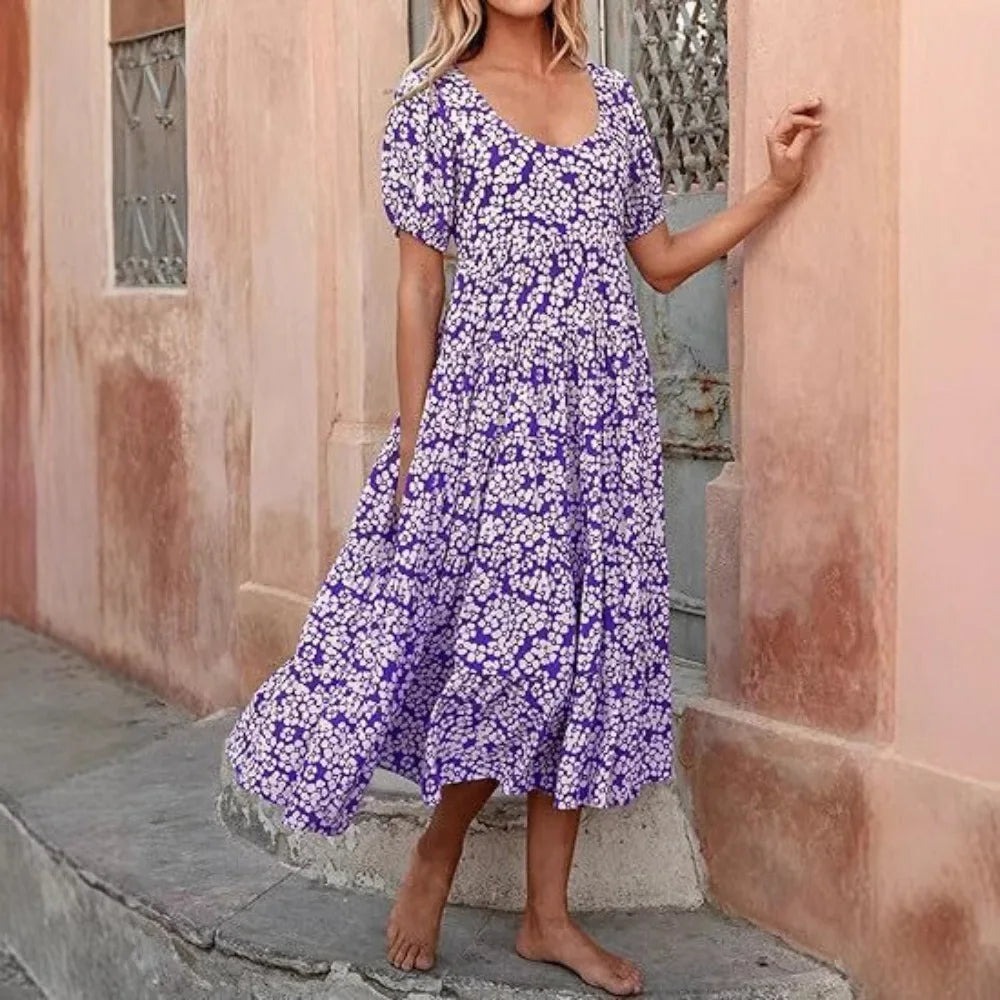 Woman wearing a purple floral dress standing against a textured wall.