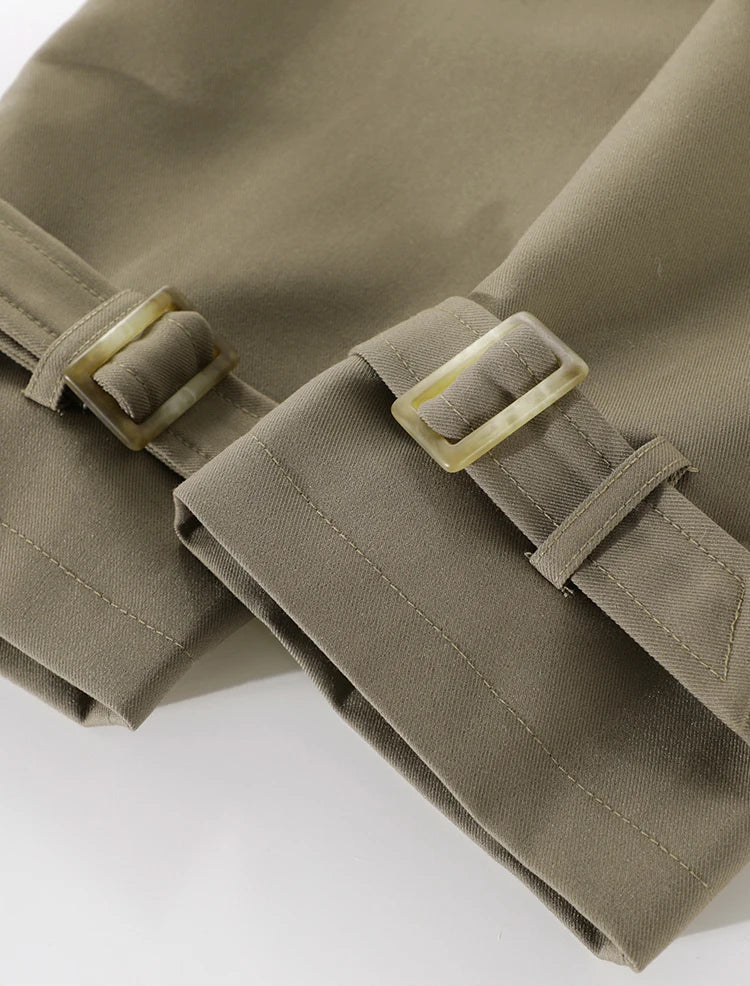 Close-up of a brown trench coat with belt and buckle on a white background