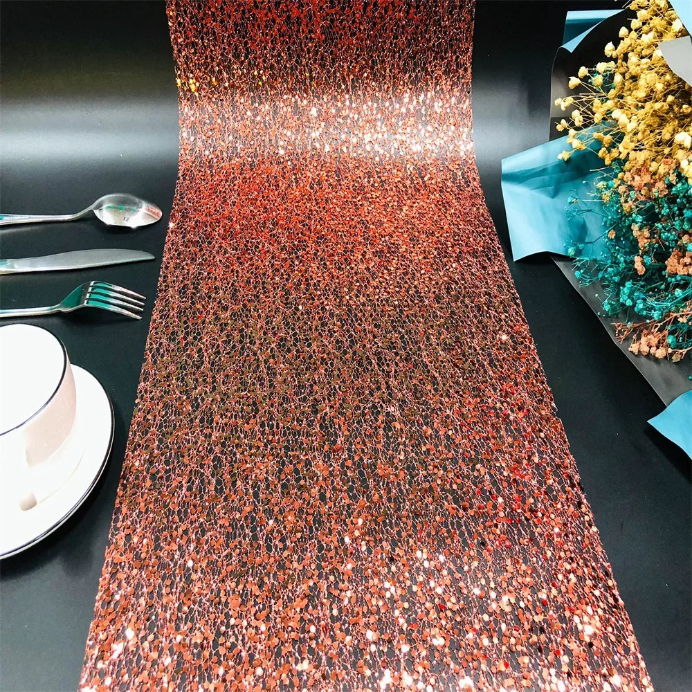 Glittery table runner on a black table with cutlery and a floral arrangement.