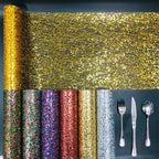 Roll of gold glitter paper with other color options and silverware on a dark background