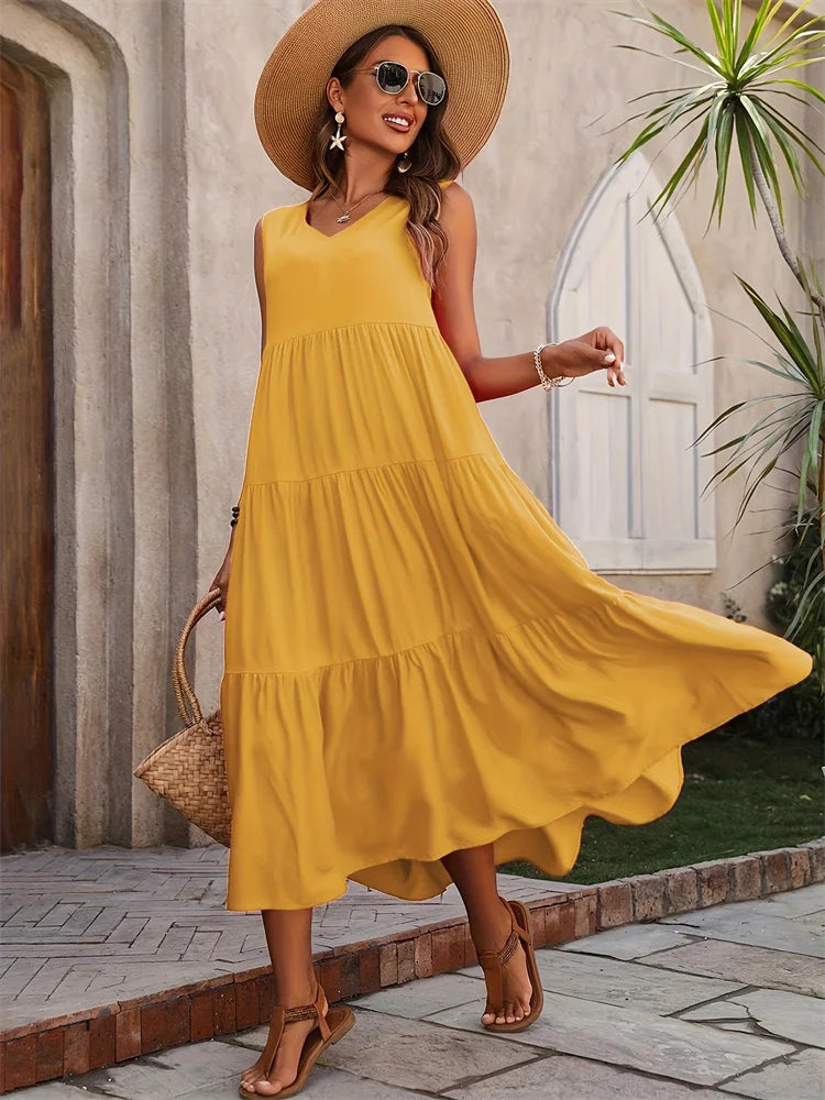 Woman in a yellow dress and sun hat standing outdoors.