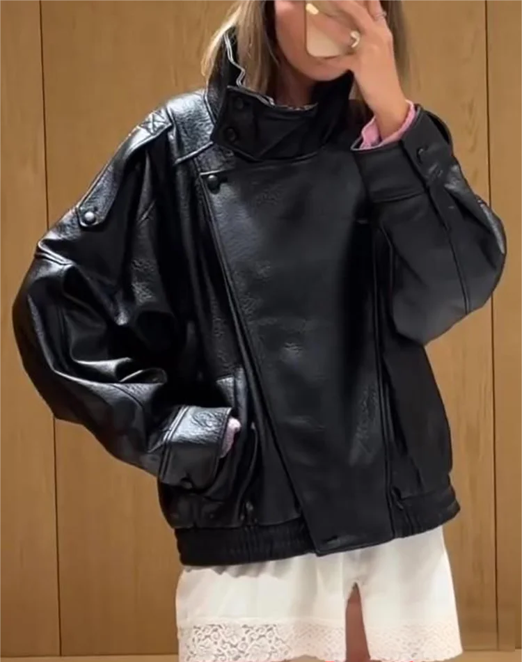 Person wearing a black leather jacket with a wooden panel background