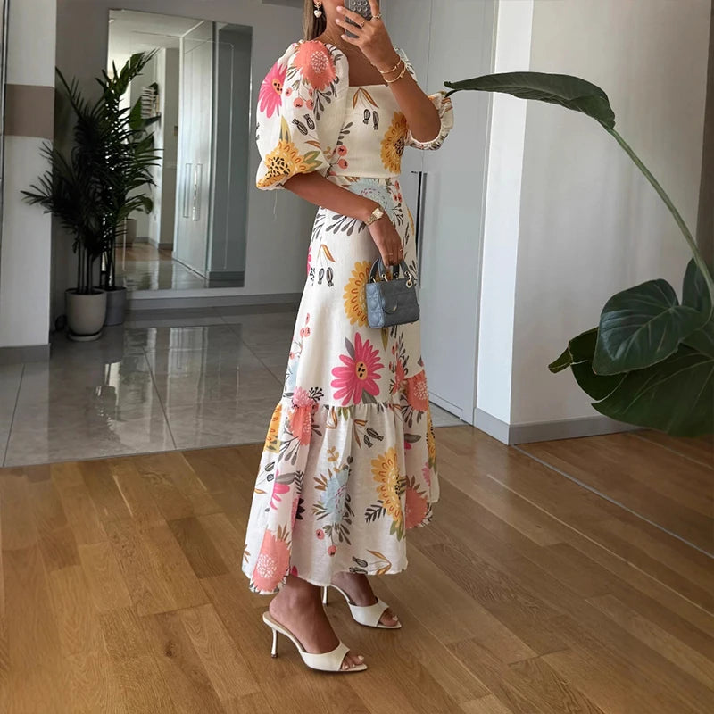 Person wearing a floral dress taking a mirror selfie in a home setting.
