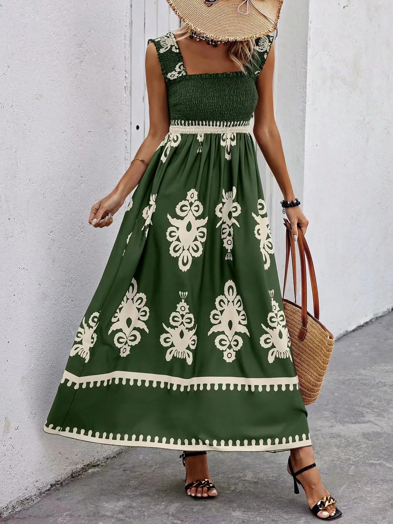 Woman wearing a green dress with white patterns against a white wall.