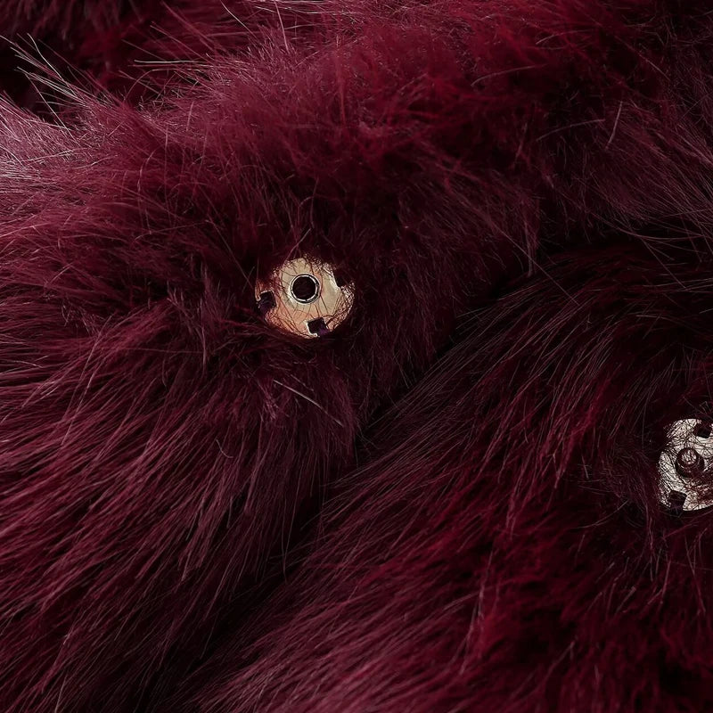 Close-up of burgundy fur with a button and floral embroidery.