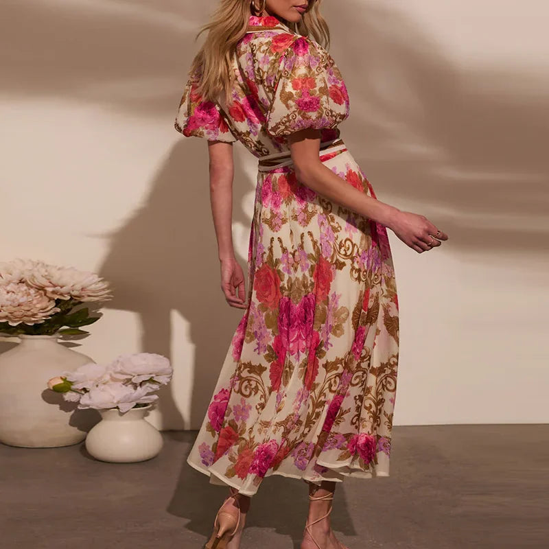 Woman wearing a floral dress standing next to a vase with flowers on a neutral background