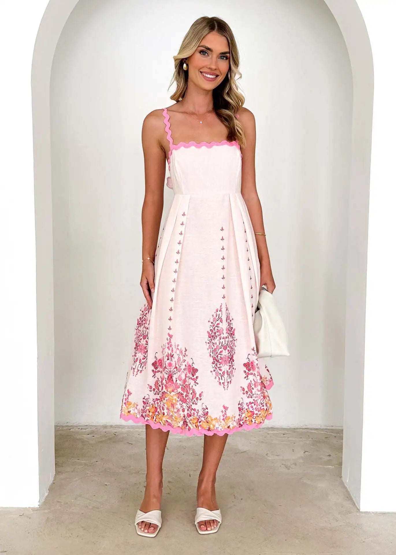 Woman wearing a white dress with pink floral patterns in a minimalistic setting