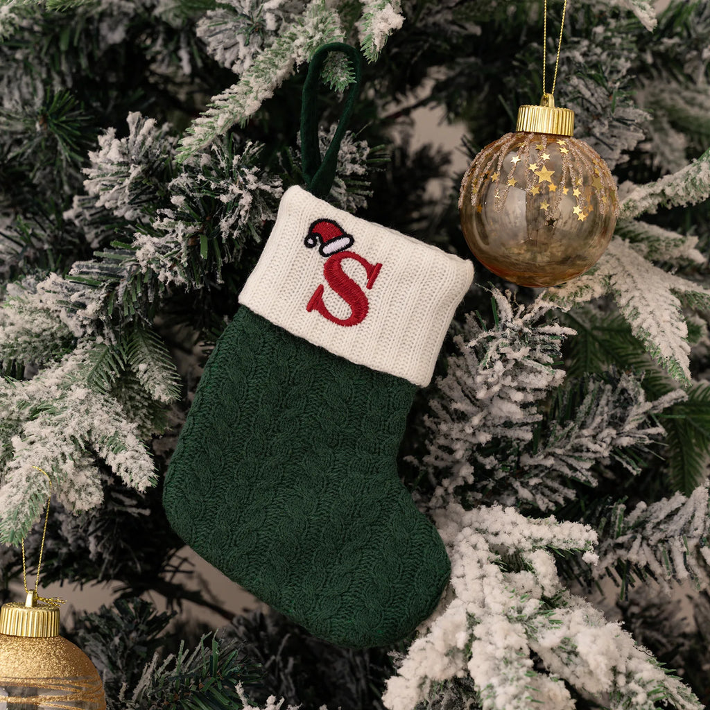 Green Christmas stocking with a red letter 'S' on a decorated tree.
