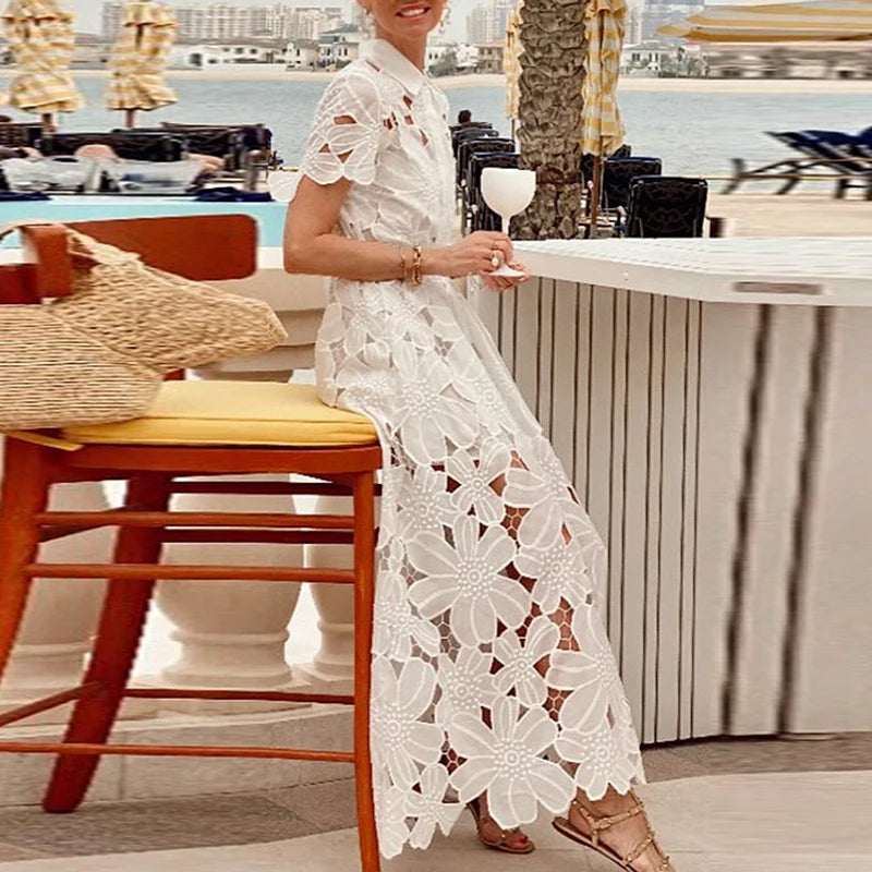Woman in a white lace dress sitting by a poolside with a cityscape in the background