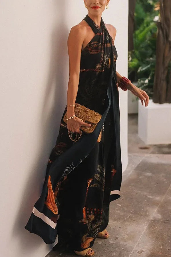 Woman in a black patterned dress holding a clutch against a white wall.