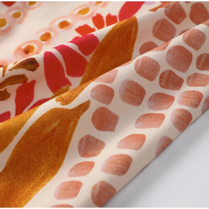 Close-up of fabric with abstract pattern featuring orange, red, and pink colors.