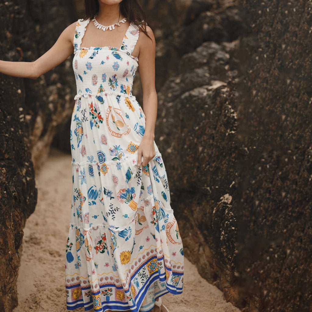 Woman wearing a floral dress standing between two rocky walls.