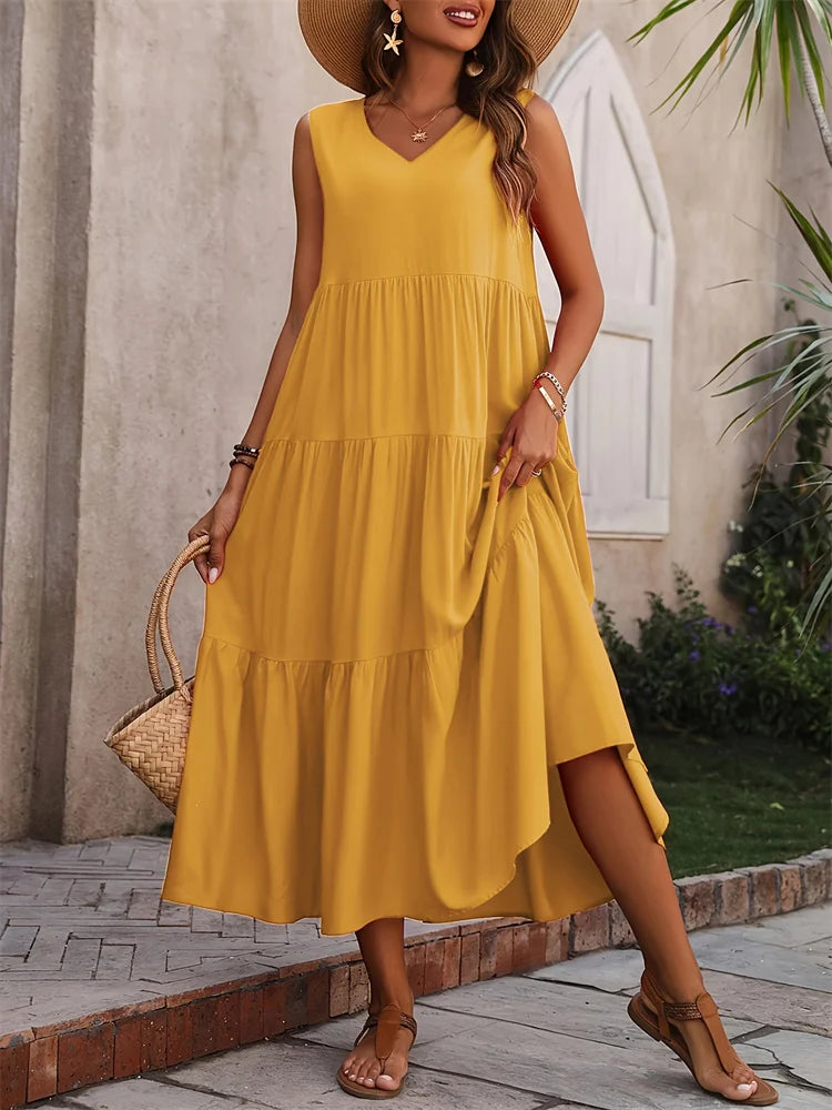 Woman wearing a yellow dress with a straw hat and sandals, standing outdoors.