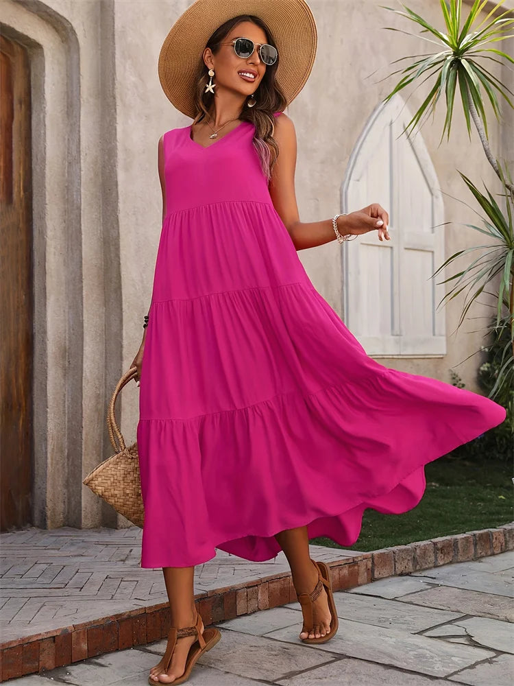 Woman in a bright pink dress and straw hat standing outdoors.