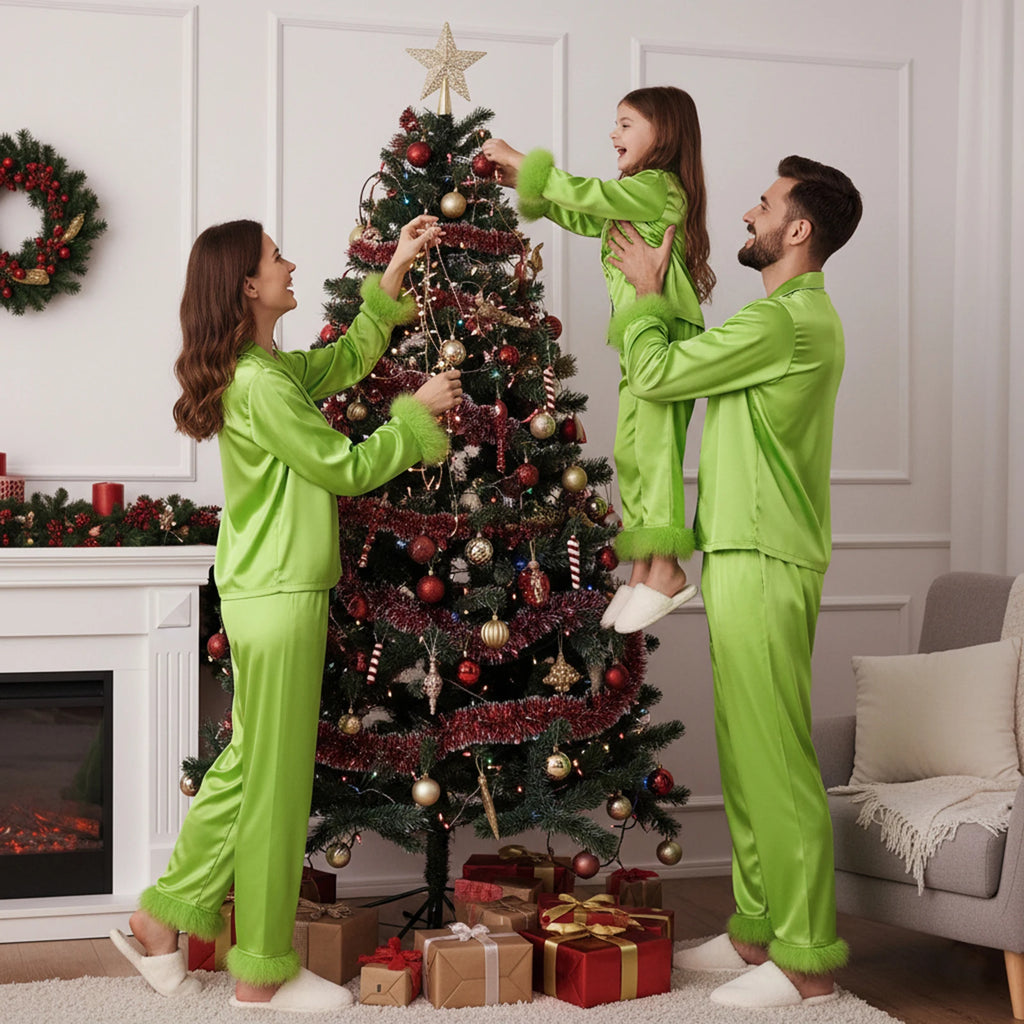 Family in matching green outfits decorating a Christmas tree in a living room.