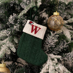 Green knitted stocking with a red 'W' ornament on a Christmas tree.