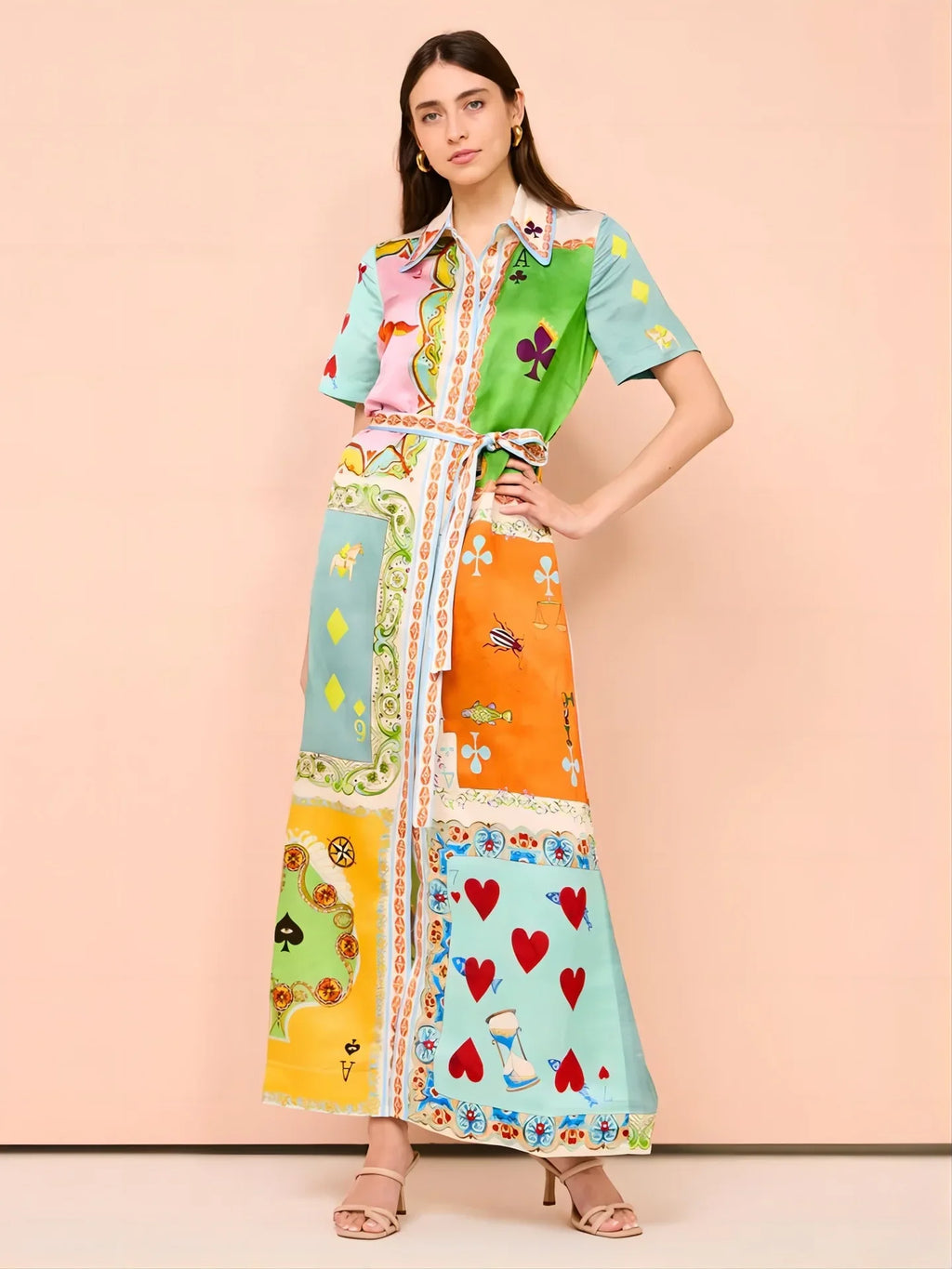 Woman wearing a colorful patchwork dress with a pattern of hearts and other designs on a beige background.