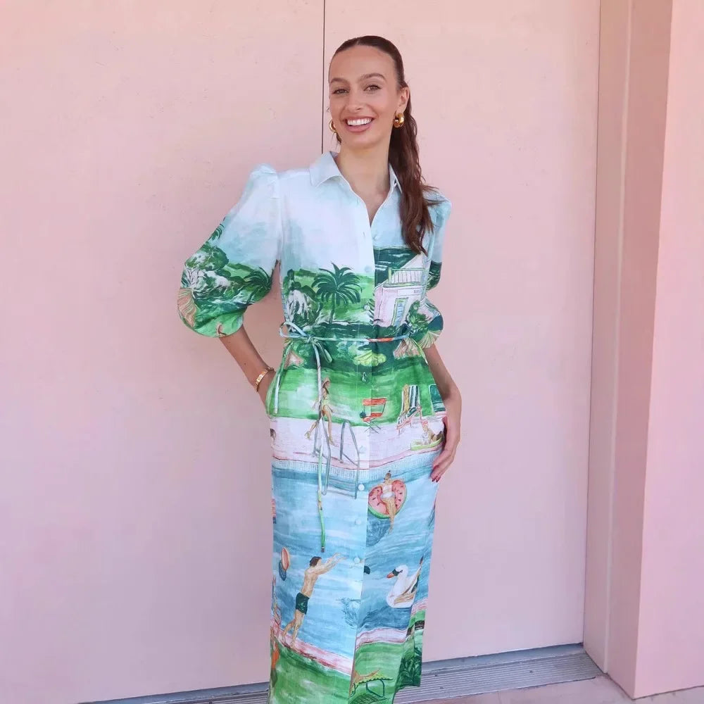 Woman wearing a colorful dress with a scenic design against a pink wall.