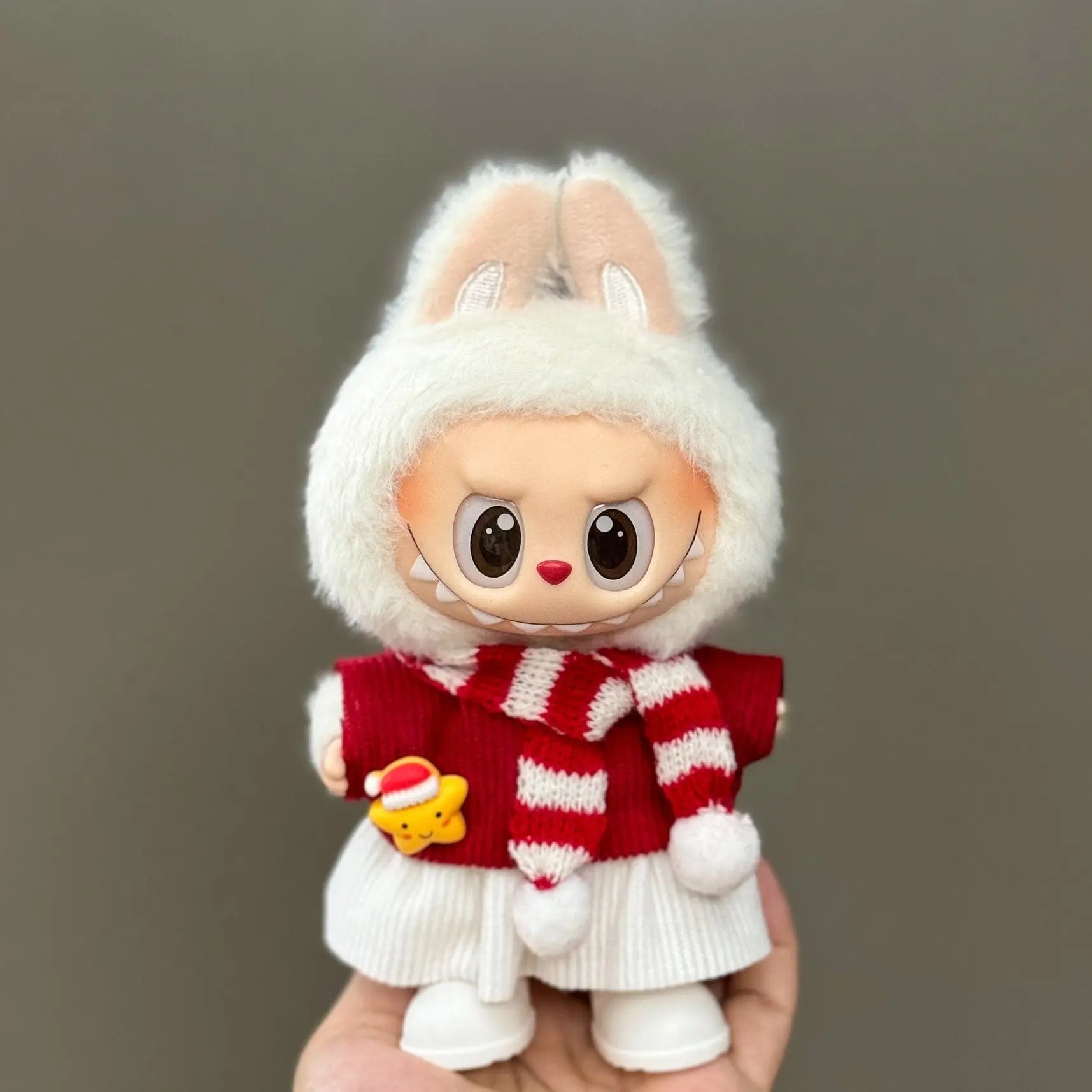 Toy figure of a rabbit wearing a red sweater with white stripes on a gray background