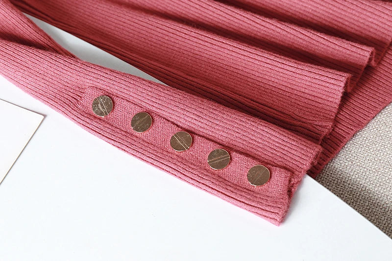 Pink ribbed fabric with gold buttons on a white surface