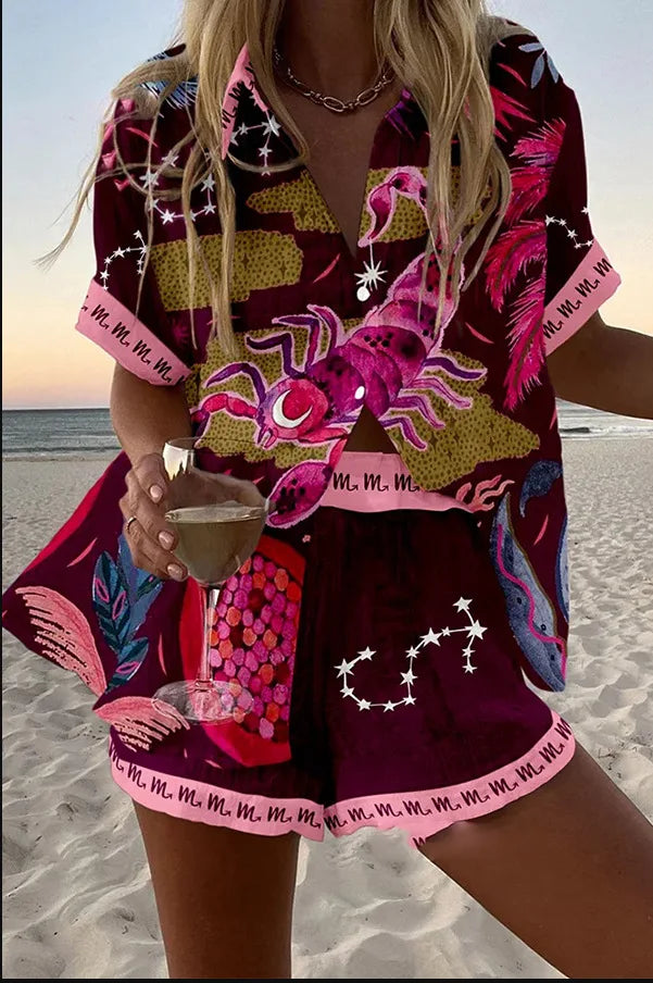 Person wearing a colorful outfit with lobster designs on a beach.