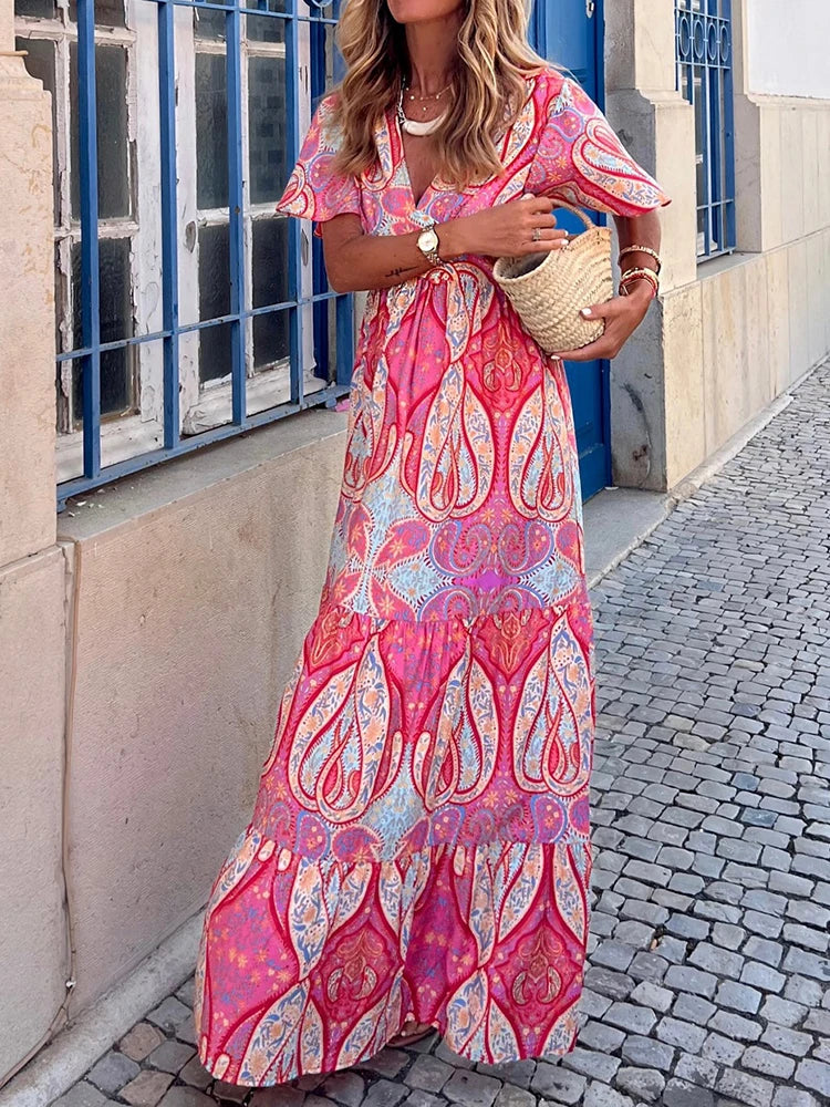 Woman wearing a pink floral dress standing on a street.