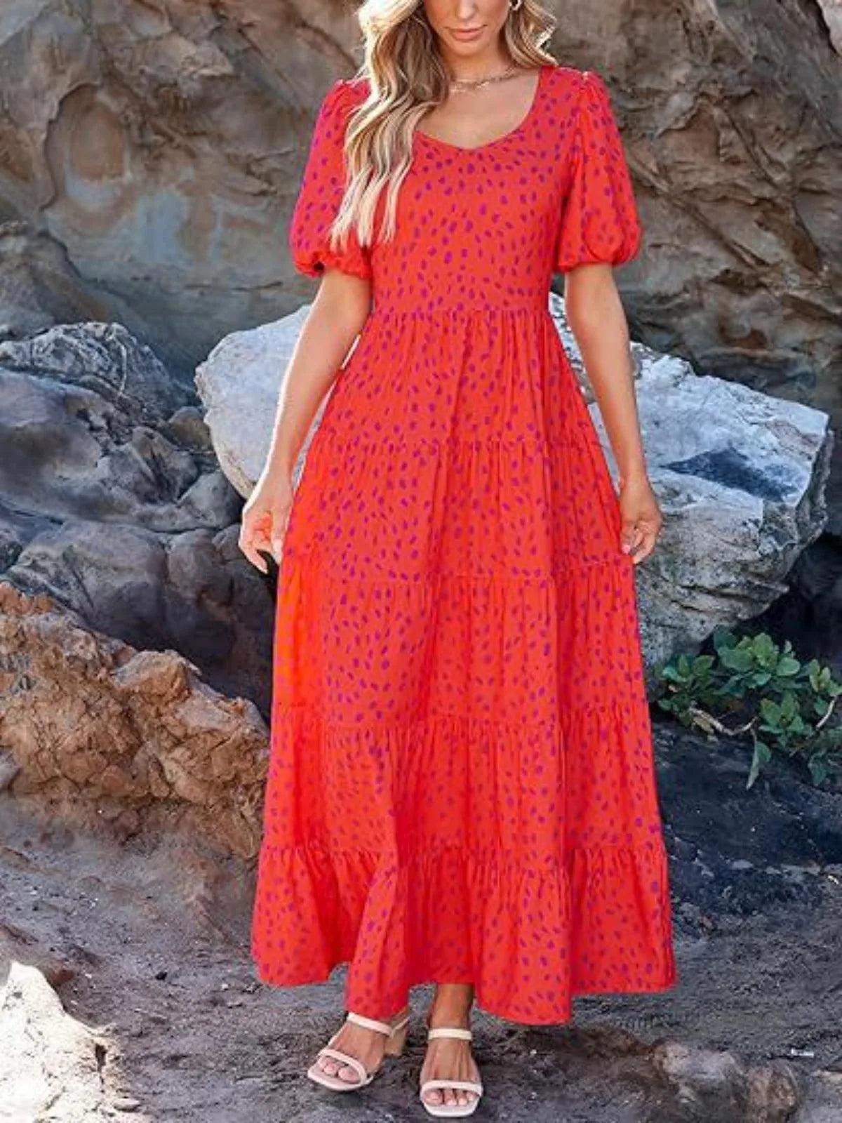 Woman wearing a red dress with puff sleeves against a rocky background