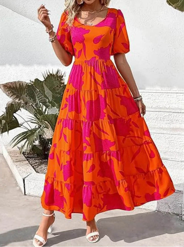 Woman wearing a bright orange and pink dress with a white background