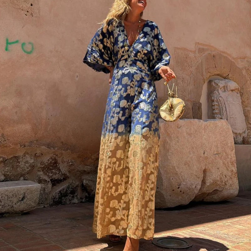 Woman in a blue and yellow floral dress standing in front of stone ruins.