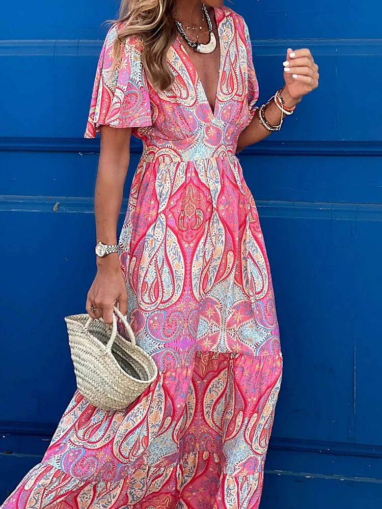 Woman wearing a pink and blue patterned dress against a blue wall.