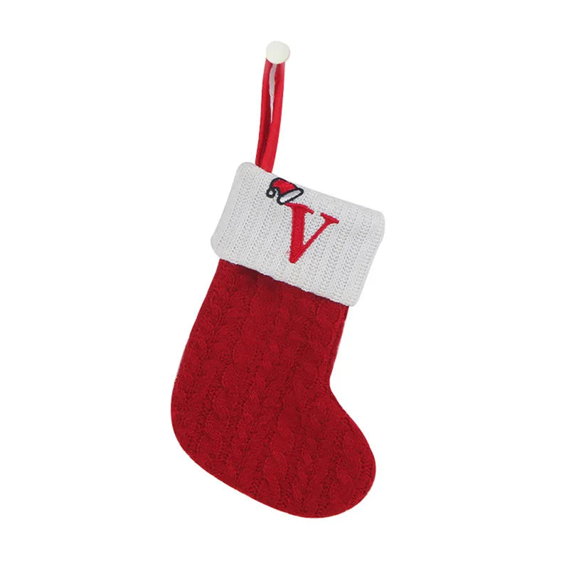 Red Christmas stocking with white cuff and embroidered letter 'V' on a white background