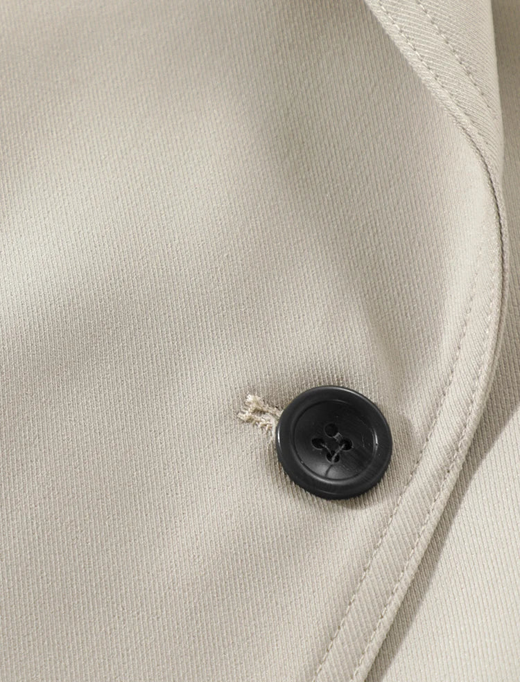 Close-up of a beige fabric with a black button on a light gray background