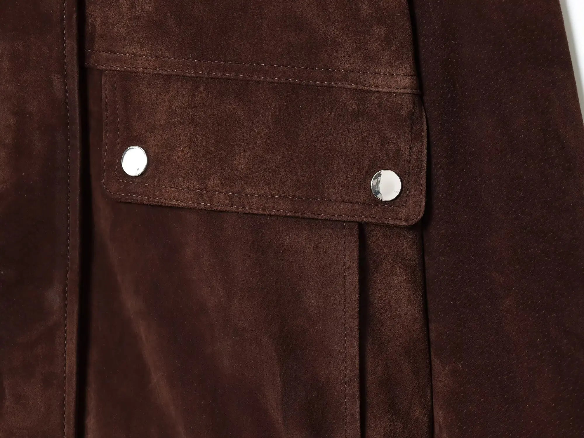 Close-up of a brown suede jacket with silver buttons.